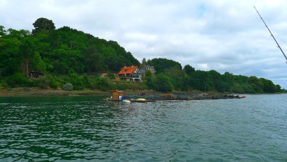 De rivieroever met een drijvende viskwekerij.